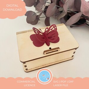 May include: A light-colored wooden box with a decorative red butterfly on top. The box has a small latch and is labeled "DIGITAL DOWNLOAD" and "COMMERCIAL LICENCE". The design is a laser file.