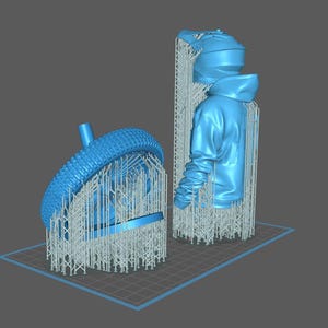 May include: A light blue 3D-printed image of a motorcycle wheel, a hoodie, and a helmet. The objects are supported by a white scaffolding structure, all set against a gray background. The wheel has a textured tire.