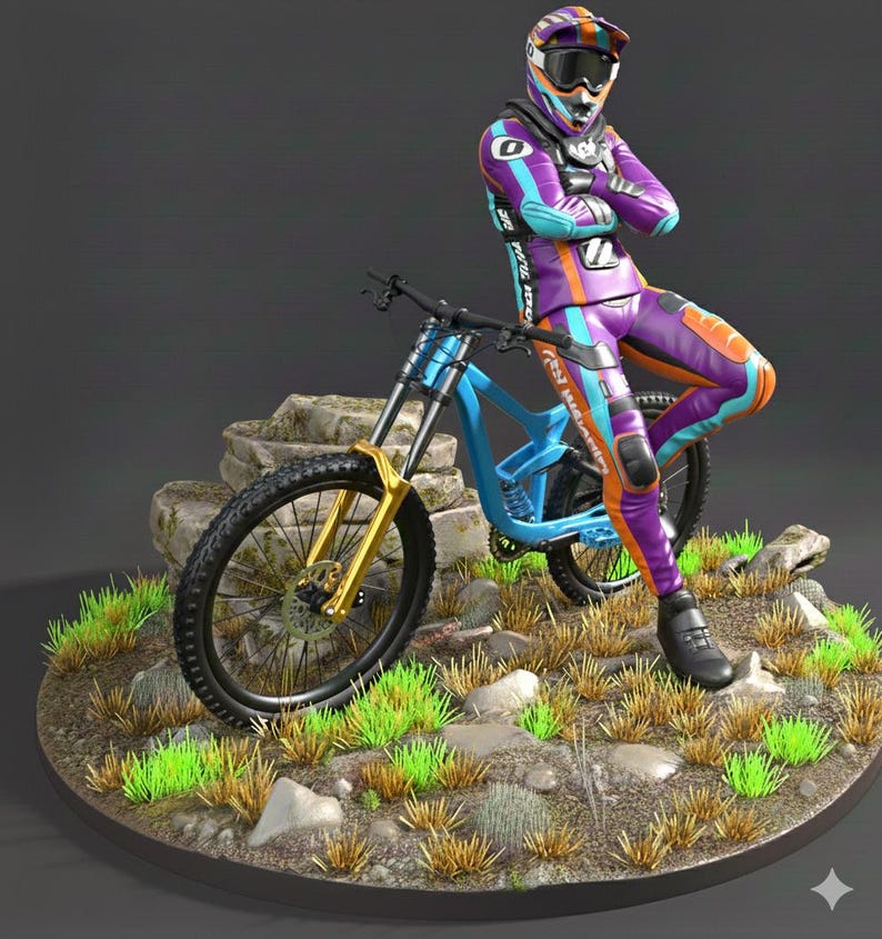 May include: A figurine of a mountain biker in a purple, orange, and blue racing suit and helmet, leaning against a blue and gold mountain bike. The bike is on a rocky terrain with green grass.
