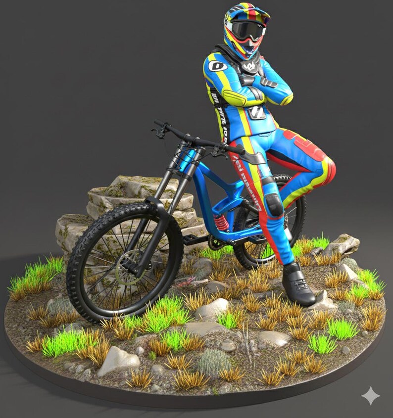 May include: A blue mountain bike with black tires and a rider in a colorful racing suit. The rider is wearing a helmet with goggles and is leaning against the bike. The bike is on a circular base with grass and rocks.