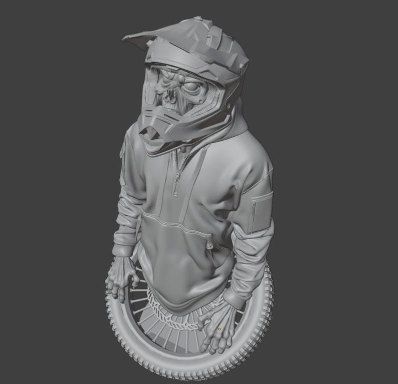 May include: A gray sculpture of a figure wearing a motocross helmet with a skull-like face, a hoodie, and gloves, resting on a tire. The helmet has a visor and the hoodie has a front pocket and a zipper. The figure's hands are resting on the tire.