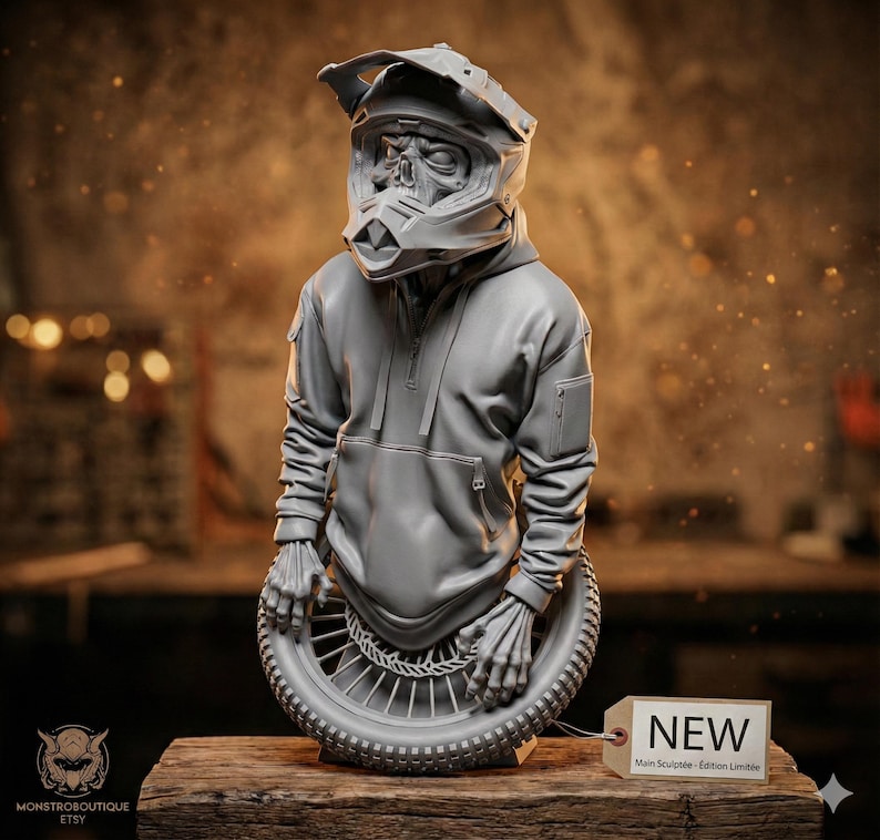 May include: A gray sculpture of a figure wearing a motorcycle helmet and hoodie, with skeletal hands holding a tire. The sculpture is displayed on a wooden surface. A tag reads "NEW".