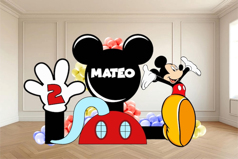 Op de afbeelding: Een grote feestuitsparing met Mickey Mouse-thema, voorzien van een zwart silhouet van een hoofd met de naam MATEO in witte letters, een rode basis met twee blauwe ovale ramen en een witte gehandschoende hand die een rood cijfer 2 vasthoudt.