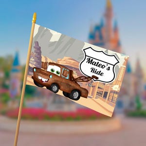 Puede incluir: Una bandera con una imagen de dibujos animados de una gr&uacute;a marr&oacute;n con ojos verdes y una cara sonriente. La bandera tiene el texto "Mateo's Ride" en un letrero blanco. El fondo muestra un paisaje des&eacute;rtico y un castillo.