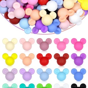 Puede incluir: Una colecci&oacute;n de cuentas de silicona con forma de rat&oacute;n, de colores vivos, incluyendo rosa, azul, amarillo y morado. Las cuentas est&aacute;n dispuestas en un mont&oacute;n y tambi&eacute;n en filas. Estas cuentas son adecuadas para manualidades y la fabricaci&oacute;n de joyas.
