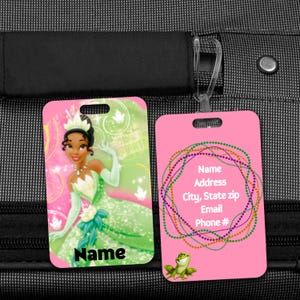 May include: Two rectangular luggage tags. One tag features a princess in a green dress with the word "Name". The other tag is pink with contact information and a frog illustration.