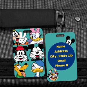May include: Two teal luggage tags. One tag features a collage of Disney characters including Mickey Mouse, Goofy, and Donald Duck. The other tag has a blue circle with contact information fields and a Mickey Mouse silhouette.