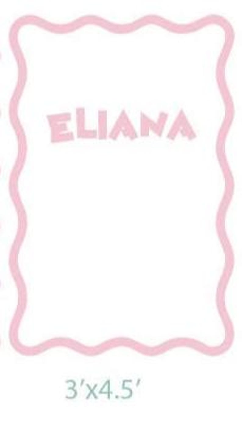 Puede incluir: Una manta rectangular blanca con un borde ondulado rosa. El nombre "ELIANA" est&aacute; impreso en letras rosas en el centro. La manta mide 91 cm por 137 cm.
