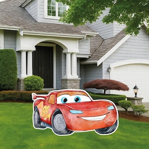 May include: A red race car yard sign featuring the number 95 in yellow on the side, large blue eyes on the windshield, and a wide smiling mouth. The car has a rear spoiler, grey wheels, and light blue headlights on a bright red body.