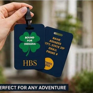 May include: Navy blue luggage tag with a green shamrock and the text "Bound for Indiana." The tag also displays the initials "HBS" and a yellow circle with text. The back of the tag has fields for name, address, and contact information.