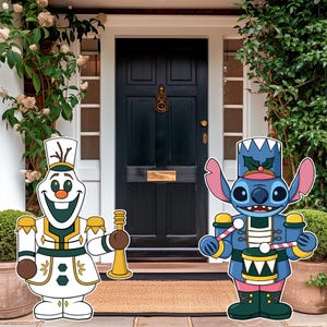 May include: Two decorative character cutouts featuring a white snowman figure with a gold trumpet and a blue alien figure with a drum. The snowman wears a white and gold uniform, while the blue alien wears a blue and green uniform with a hat.