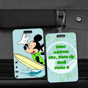 May include: Two light blue luggage tags. One tag features Mickey Mouse surfing, with the name "Name" printed vertically. The other tag has a tropical design with space for contact information.