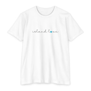 Può includere: T-shirt bianca con la scritta "island love" in stile scritto a mano, con un piccolo cuore blu che sostituisce la lettera "o". La maglietta è realizzata in materiale morbido e ha maniche corte.