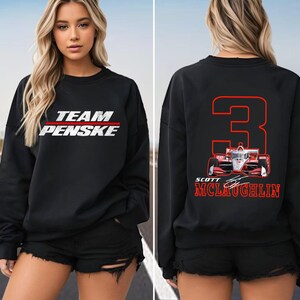 Puede incluir: Una sudadera negra de manga larga con el texto blanco TEAM PENSKE en la parte delantera. La parte trasera muestra un gran n&uacute;mero 3 rojo, un gr&aacute;fico de coche de carreras rojo y blanco, y el texto rojo SCOTT MCLAUGHLIN con una firma.