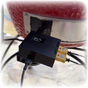 May include: A black "GRILL MEAT" device with a small screen and two yellow temperature probes. The device is connected to a red grill and a black cable. The screen displays numbers and text.