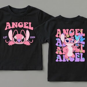 May include: A black short-sleeved t-shirt featuring a pink character graphic. The front displays the text ANGEL EST 2004. The back shows the character surrounded by repeating ANGEL text and small flower icons in shades of pink, purple, and blue.