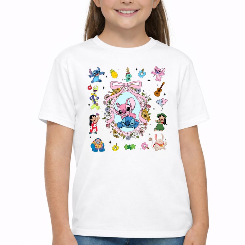 May include: A white short-sleeved t-shirt featuring a central oval frame decorated with flowers and a pink bow, containing illustrations of Stitch and Angel. Surrounding the frame are various small character icons, including Lilo, Scrump, and other figures.