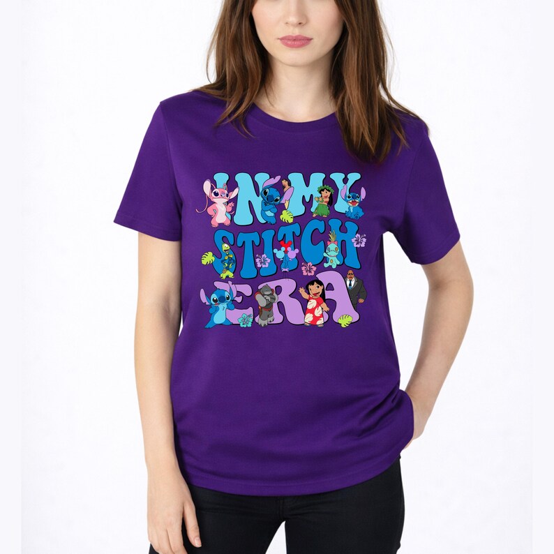Pode incluir: Uma t-shirt roxa de manga curta com uma impress&atilde;o gr&aacute;fica com o texto IN MY STITCH ERA. O design inclui v&aacute;rias personagens de desenhos animados da franquia Lilo e Stitch, intercaladas com flores tropicais e folhas verdes.