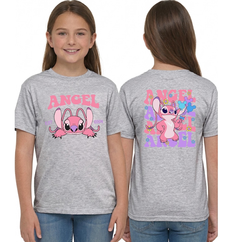 May include: A heather grey short-sleeve t-shirt featuring a pink character graphic on the front with the text ANGEL and EST 2004. The back displays a full-body pink character graphic surrounded by small blue and yellow flowers and the word ANGEL.