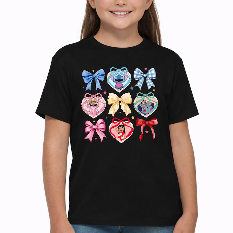 May include: A black short-sleeve t-shirt featuring a graphic print of various colorful bows and heart-shaped frames. Inside the hearts are illustrations of Stitch, Angel, and Lilo from Lilo and Stitch, accented by small scattered stars.