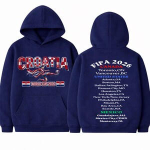 May include: Navy blue hoodie featuring "CROATIA" in red and white, with a soccer player graphic and "WORLD CUP 2026" text. The back displays "FIFA 2026" and host cities in Canada, the United States, and Mexico. A hooded sweatshirt.