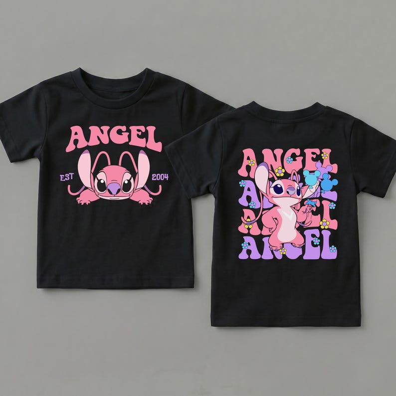 May include: A black short-sleeved t-shirt featuring a pink character graphic. The front displays the text ANGEL EST 2004. The back shows the character surrounded by repeating ANGEL text and small flower icons in shades of pink, purple, and blue.