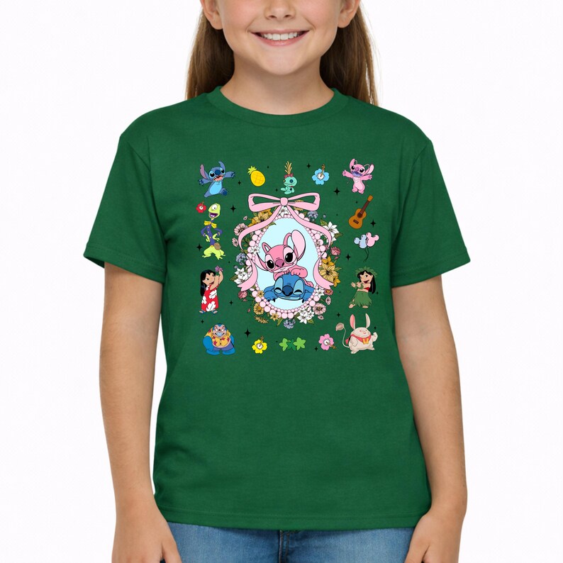 May include: A dark green short-sleeve t-shirt featuring a central oval frame decorated with flowers and a pink bow, containing illustrations of Stitch and Angel. The surrounding area includes various small character icons and tropical motifs.