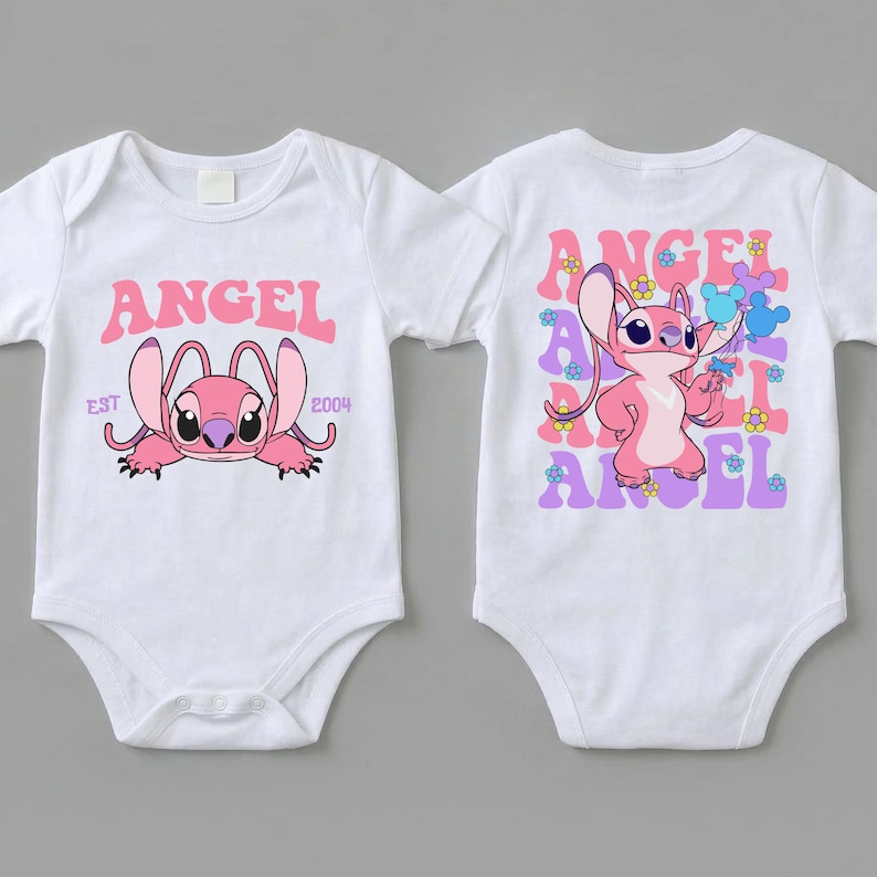 May include: Two white short-sleeved baby bodysuits. The left one features a pink Angel character with the text ANGEL EST 2004. The right one displays a standing pink Angel character surrounded by repeating purple ANGEL text and small colourful flowers.