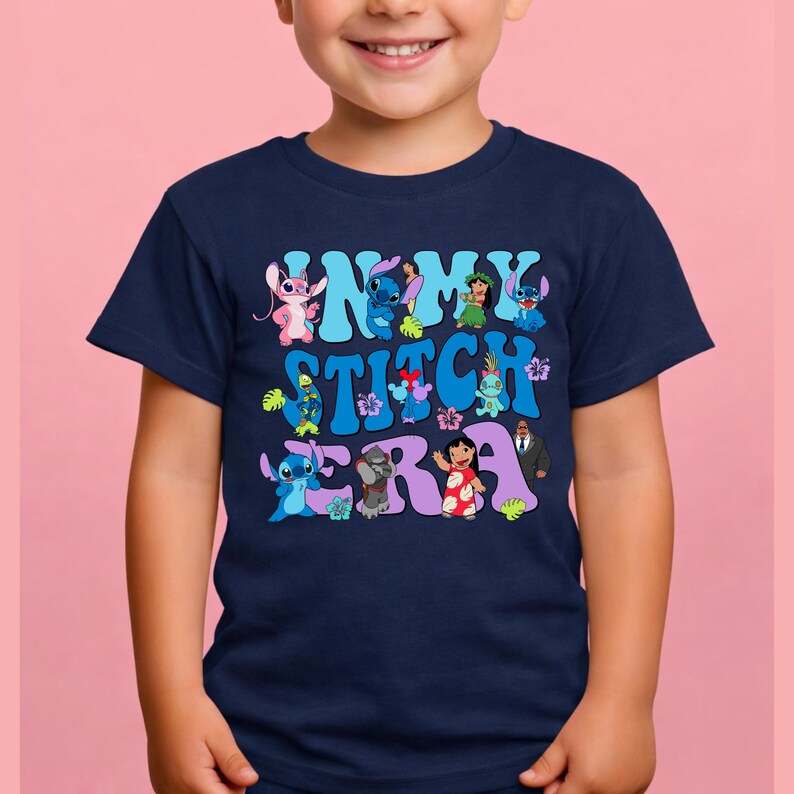 Pode incluir: Uma t-shirt azul-marinho de manga curta com uma estampa gr&aacute;fica que inclui o texto "IN MY STITCH ERA" em azul-claro e roxo. O design apresenta v&aacute;rias personagens de desenhos animados da franquia Lilo e Stitch e flores tropicais.