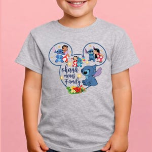 May include: A heather gray short-sleeve t-shirt featuring a graphic inside a Mickey Mouse ear outline. The design includes the blue character Stitch, the character Lilo, and the text "ohana means Family" with colorful tropical hibiscus flowers.