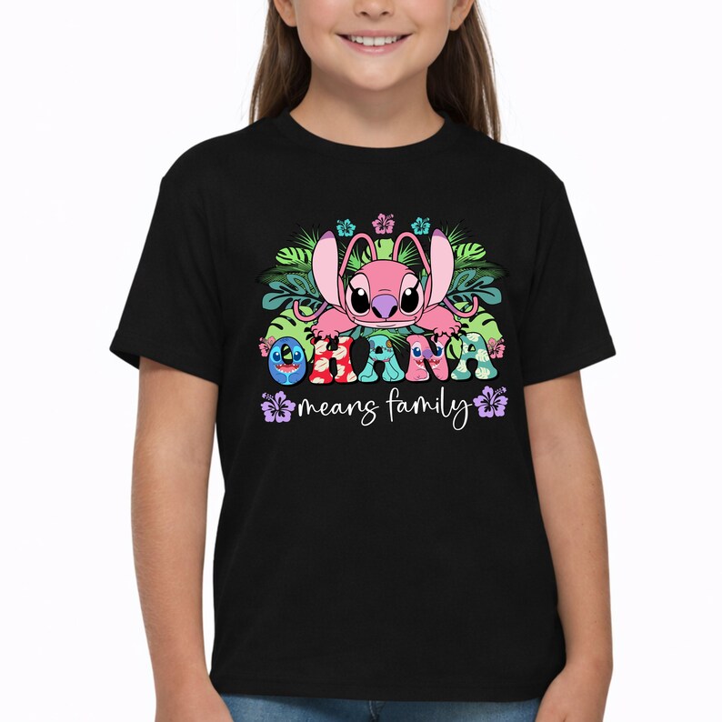 May include: A black short-sleeve t-shirt featuring a graphic of a pink character with large ears surrounded by green tropical leaves and colorful hibiscus flowers. The text OHANA means family is printed in a multi-colored, patterned font.