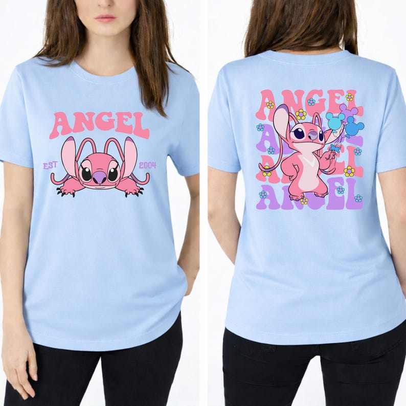May include: A light blue t-shirt featuring a graphic of the pink character Angel on the front with the text ANGEL EST 2004. The back displays a larger graphic of Angel holding balloons surrounded by repeating text and small colourful flower icons.