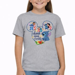 May include: A heather gray t-shirt featuring a graphic of a Mickey Mouse ear silhouette containing illustrations of Lilo and Stitch. The text "ohana means family" is printed in the center, accompanied by small yellow stars and tropical flowers.