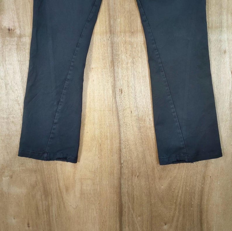 Pu&ograve; includere: Un paio di pantaloni grigio scuro con una leggera svasatura sul fondo. I pantaloni sono realizzati in un tessuto liscio e uniforme e sono esposti su una superficie di legno marrone chiaro. Il design &egrave; classico e semplice.