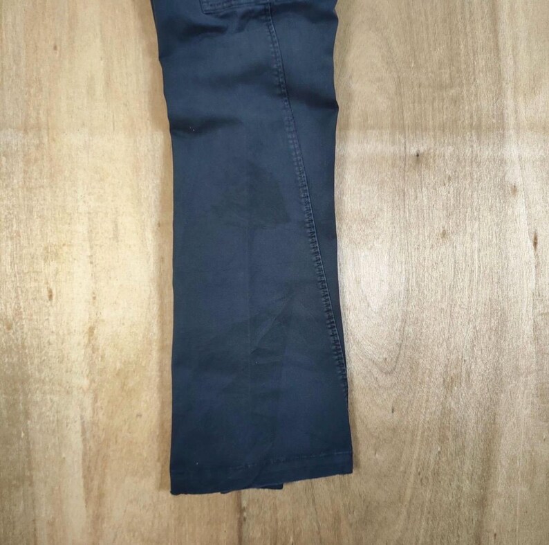 Pu&ograve; includere: Pantaloni blu navy scuro con design a gamba dritta. I pantaloni sono realizzati in un tessuto resistente e presentano uno stile classico e casual. I pantaloni sono mostrati su una superficie di legno marrone chiaro.