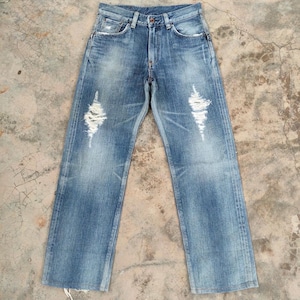 May include: Light blue denim jeans with distressed details, including ripped sections on the front of the legs. The jeans have a classic five-pocket design and a button and zipper closure. The denim has a faded wash.