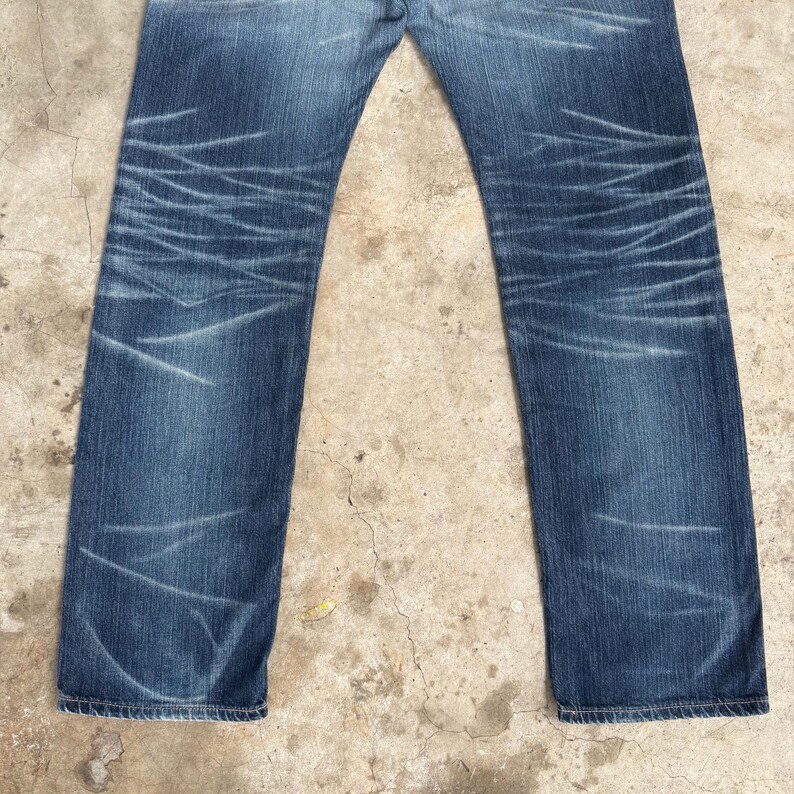 Op de afbeelding: Blauwe denim jeans met vervaagde plekken en distressed details. De jeans hebben een klassiek ontwerp met vijf zakken en een rechte pijp. De denim heeft een medium wassing met lichtere plekken die een versleten look cre&euml;ren. De jeans zijn geschikt voor casual wear.