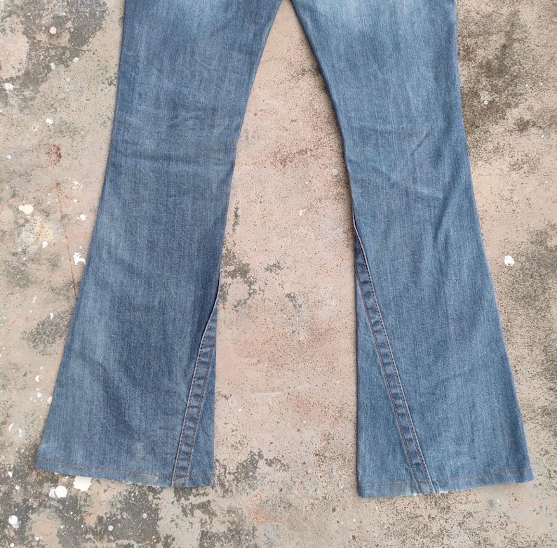 May include: A trio of cream-glazed ceramic mugs with a speckled finish. Each mug is adorned with a hand-painted design: a blue and green leaf, a yellow flower, and a red berry. The mugs have a simple, modern design.