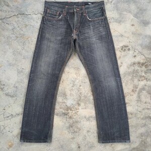 Pu&ograve; includere: Jeans in denim lavato scuro con taglio dritto. I jeans hanno un classico design a cinque tasche, cuciture arancioni e chiusura con bottone e cerniera. Il denim ha un aspetto sbiadito.