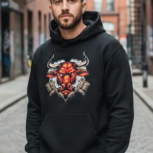 May include: Black hooded sweatshirt with a red and orange bull graphic on the front. The bull has large horns and is surrounded by smoke. The sweatshirt has a front pocket and a drawstring hood.