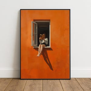 May include: A framed wall art print featuring a vibrant orange wall with a single open window. A figure sits in the window frame, holding an open book in front of their face. The figure wears a white long-sleeved top and dark shorts, with bare legs.