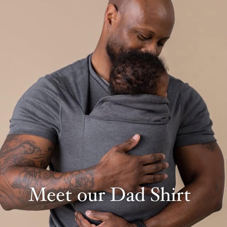 Peut inclure: T-shirt gris pour papa avec porte-b&eacute;b&eacute; int&eacute;gr&eacute;. Le t-shirt &agrave; manches courtes est dot&eacute; d'une poche pour maintenir un b&eacute;b&eacute;. Le texte "Meet our Dad Shirt" est affich&eacute; en bas de l'image.