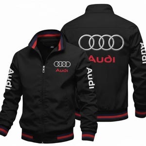 May include: Black zip-up jacket with the Audi logo on the front and back. The jacket has a stand-up collar with red and blue trim, and the Audi name is printed in red. The sleeves also feature the Audi name in white.