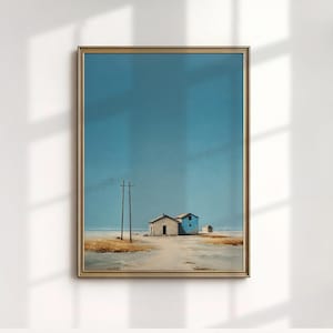 May include: A framed landscape painting depicts a serene coastal scene. Two small buildings, one white and one blue, stand on a sandy shore under a vast blue sky. Two utility poles are in the foreground. The artwork is encased in a gold frame.
