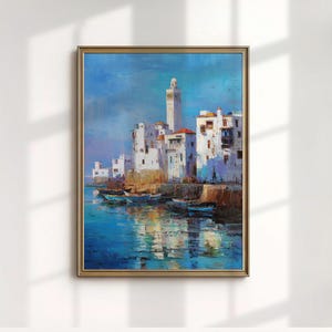 May include: Oil painting of a coastal town with white buildings, red rooftops, and a tall minaret. The artwork depicts boats in the water and reflections of the buildings. The painting is framed in a gold-colored frame.