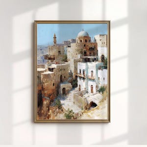 Może przedstawiać: Oprawiony obraz przedstawiający krajobraz miejski Bliskiego Wschodu z beżowymi i białymi budynkami, kopułą i minaretem na tle jasnoniebieskiego nieba. Dzieło sztuki znajduje się w złotej ramie, prezentując szczegółową scenę architektoniczną.