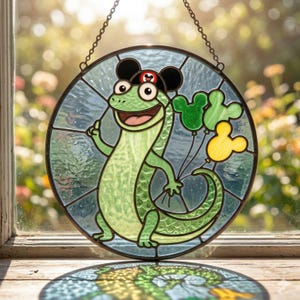 May include: A round stained glass window featuring a cartoon lizard wearing a black hat with Mickey Mouse ears and holding Mickey Mouse-shaped balloons. The lizard is green with a smiling face. The balloons are green and yellow.