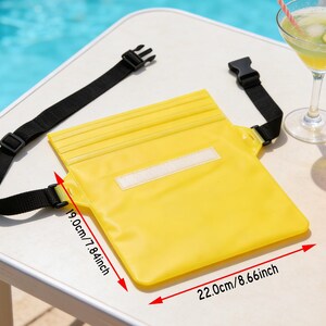 Op de afbeelding: Een felgele waterdichte tas, 22,0 cm breed en 19,0 cm hoog, met een zwarte verstelbare riem en gespsluiting. De tas heeft een witte rechthoekige patch aan de voorkant. De tas is ontworpen om items tegen water te beschermen.