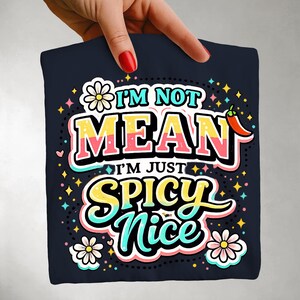 以下が含まれることがあります： 「I'M NOT MEAN I'M JUST SPICY NICE」のテキストがカラフルなレトロデザインでプリントされた、ネイビーブルーのTシャツ。花、星、唐辛子のグラフィックが含まれています。カジュアルなTシャツのための楽しくて遊び心のあるデザイン。