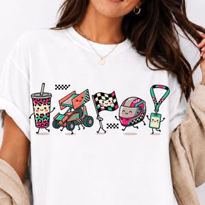 Könnte beinhalten: Ein weißes T-Shirt mit einem Grafikdruck von fünf anthropomorphen Rennsport-Gegenständen: ein Becher mit Leopardenmuster, ein Sprint-Car, eine Zielflagge, ein Rennhelm und ein Schlüsselband mit Ausweis, alle mit lächelnden Gesichtern.